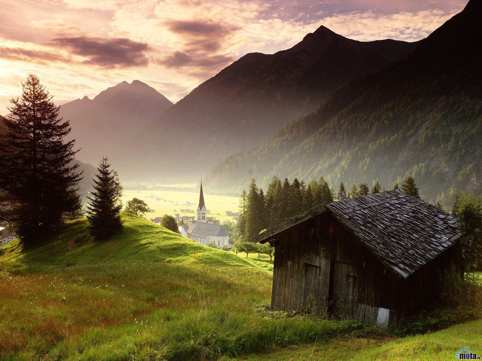 A view over a small town in a valley. The text hovering over the image reads "Looking for more? Keep scrolling". 